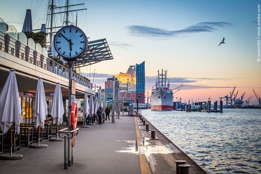 Eine Standuhr an einer Hafenpromenade. 